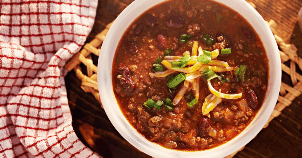 Hearty bowl of homemade chili topped with cheese and green onions from John Mull’s chili recipe blog