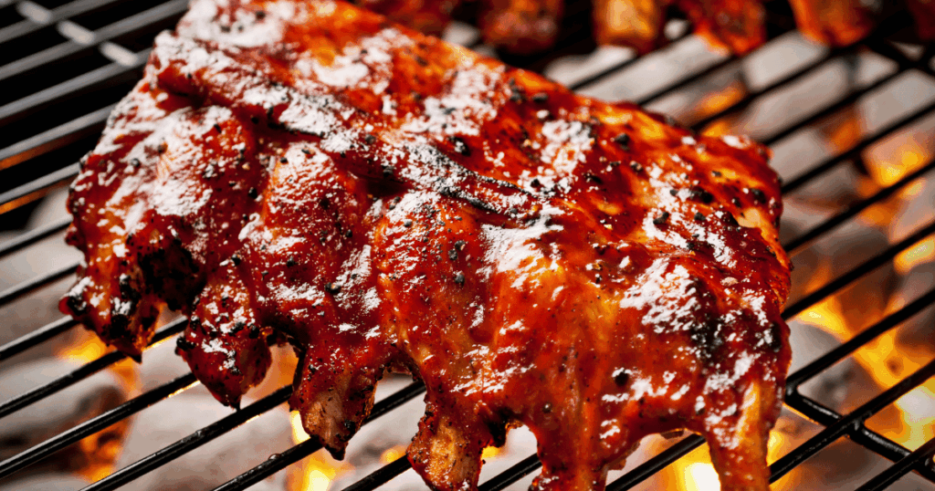 Grilled beef back ribs with BBQ sauce cooking over flame at John Mull’s Meats