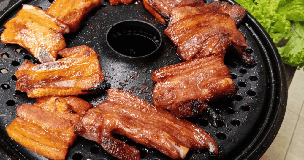 Korean Barbecue pork grilling on a hot plate with rich caramelized glaze