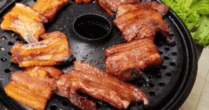 Korean Barbecue pork grilling on a hot plate with rich caramelized glaze