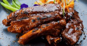 Close-up of glazed BBQ ribs with caramelized sauce, served with garnish