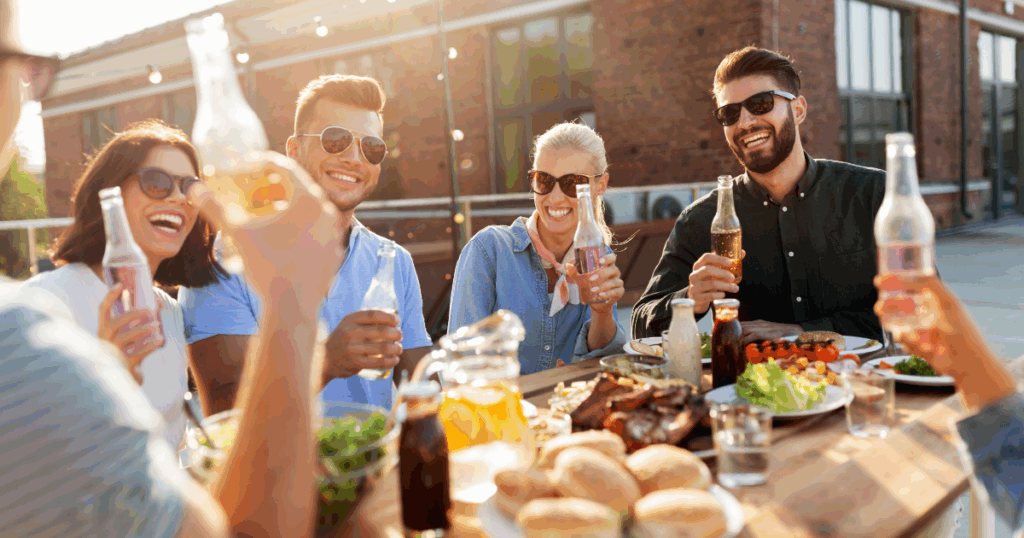Group of friends enjoying a summer BBQ party with food and drinks at an outdoor table in Las Vegas