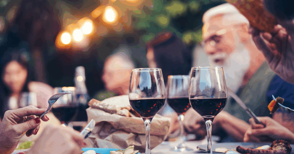 Outdoor dinner party with red wine and BBQ dishes, illustrating a step-by-step guide to pairing wine with barbecue