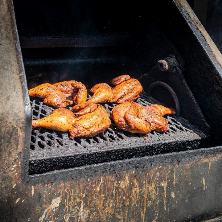 Close-up of grilled BBQ ribs sizzling on the grill at a catered event from John Mull’s Meats — perfect for those planning a flavorful and successful BBQ.
