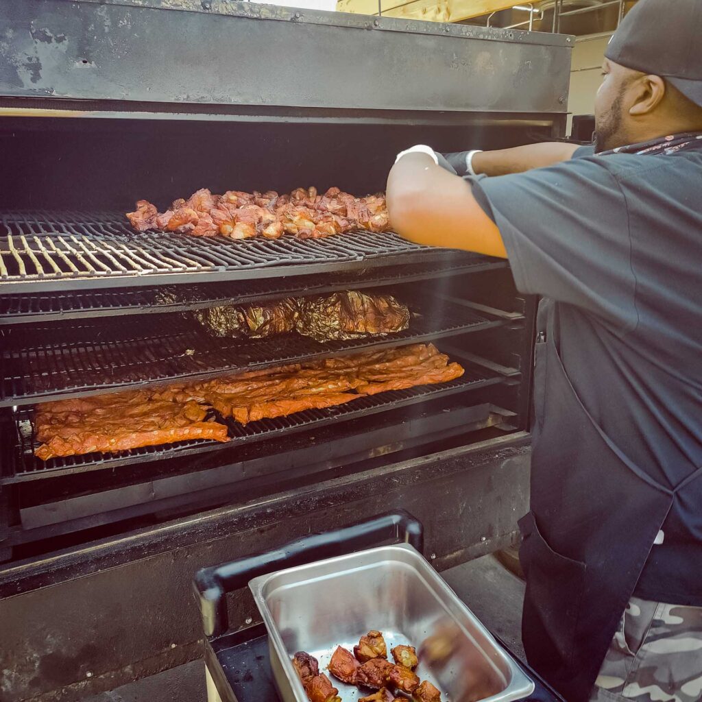 Burnt ends and ribs cooking on open flame grill at John Mull’s BBQ fundraiser event in Las Vegas