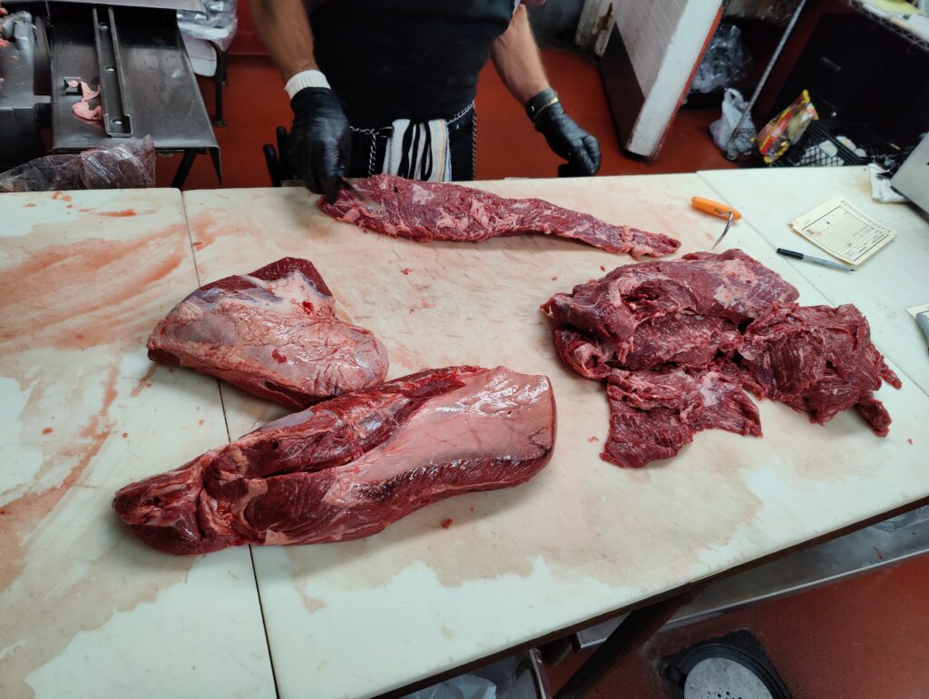 High-quality beef cuts being expertly prepared by the butcher at John Mull’s Meats in Las Vegas.