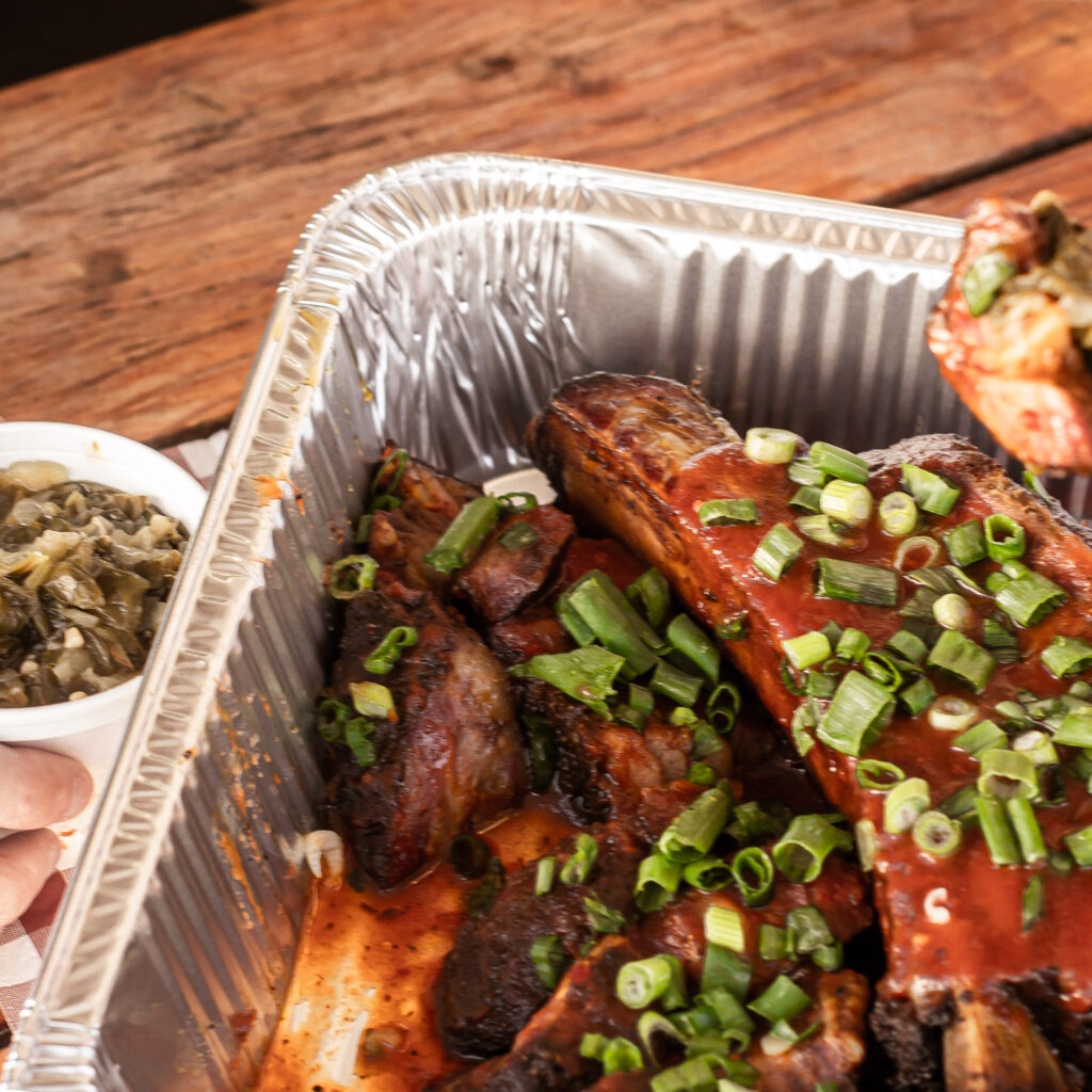 BBQ catering plate from John Mull’s Meats featuring ribs, pulled pork, and classic sides like mac and cheese, baked beans, and coleslaw