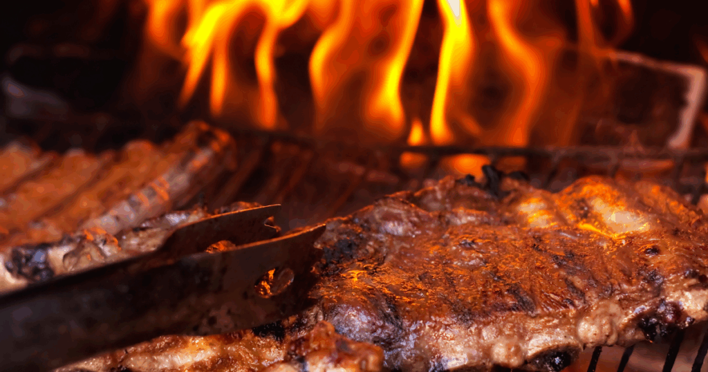 Flame-grilled BBQ ribs sizzling over open fire after smoking low and slow at John Mull’s BBQ catering in Las Vegas