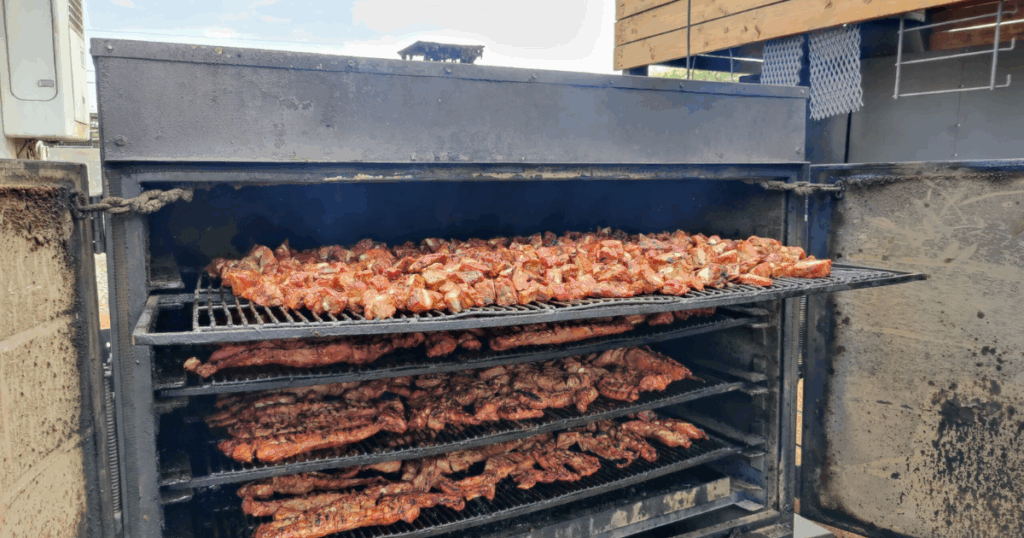 Wood-smoked ribs and southern BBQ service meats inside a commercial smoker at John Mull’s BBQ in Las Vegas