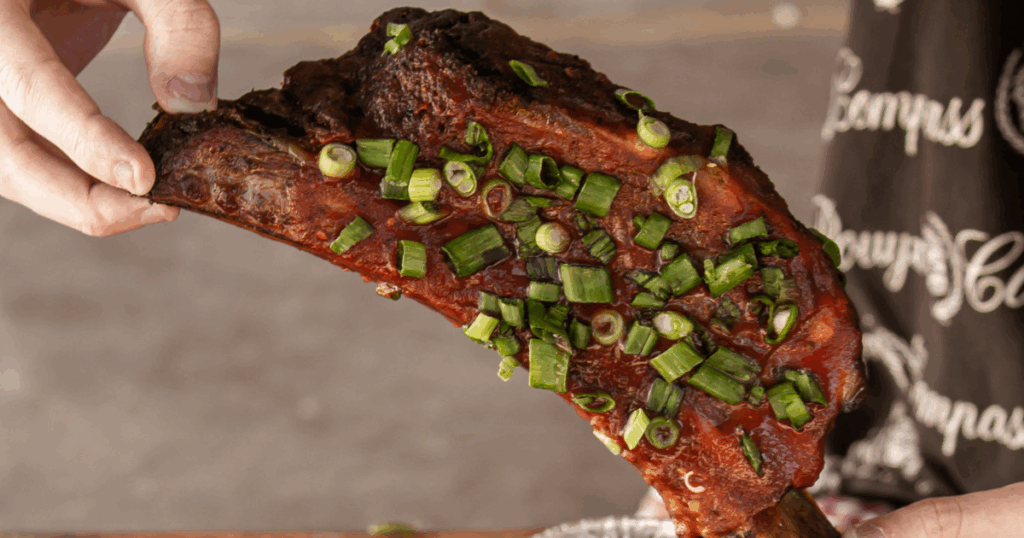Hand holding a smoked rib tip topped with green onions at John Mull’s Road Kill Grill near North Las Vegas