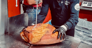Butcher at John Mull’s Meats cutting the best fresh Thanksgiving ham with precision, nominated Best Butcher Shop in USA
