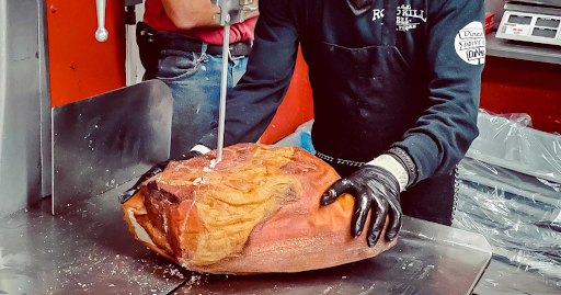 Butcher at John Mull’s Meats cutting the best fresh Thanksgiving ham with precision, nominated Best Butcher Shop in USA