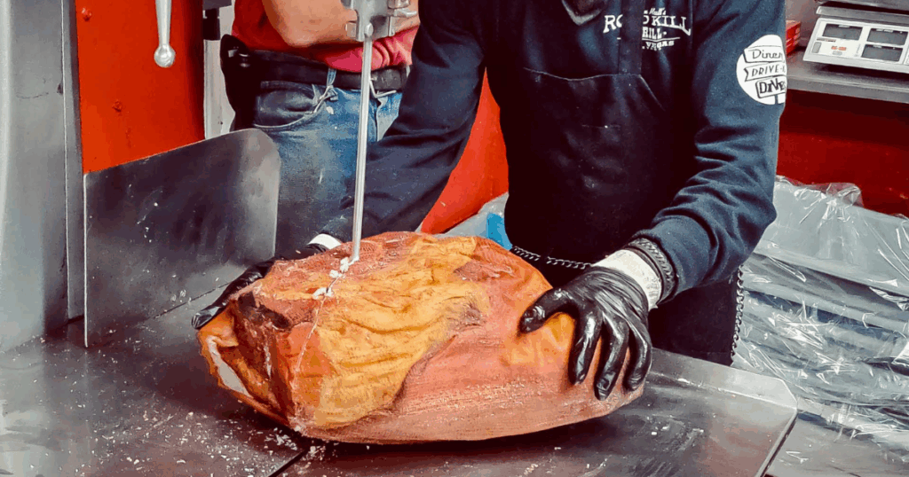 Butcher slicing smoked ham at John Mull’s Meat Market in Las Vegas for Thanksgiving catering orders.