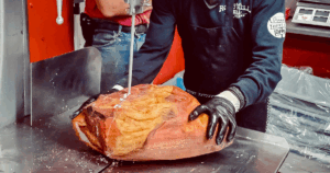 Butcher slicing smoked ham at John Mull’s Meat Market in Las Vegas for Thanksgiving catering orders.