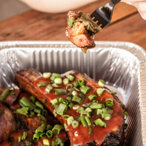 Close-up of smoked BBQ ribs topped with green onions from John Mull’s Meats in Las Vegas, served fresh for Super Bowl catering and game-day parties.
