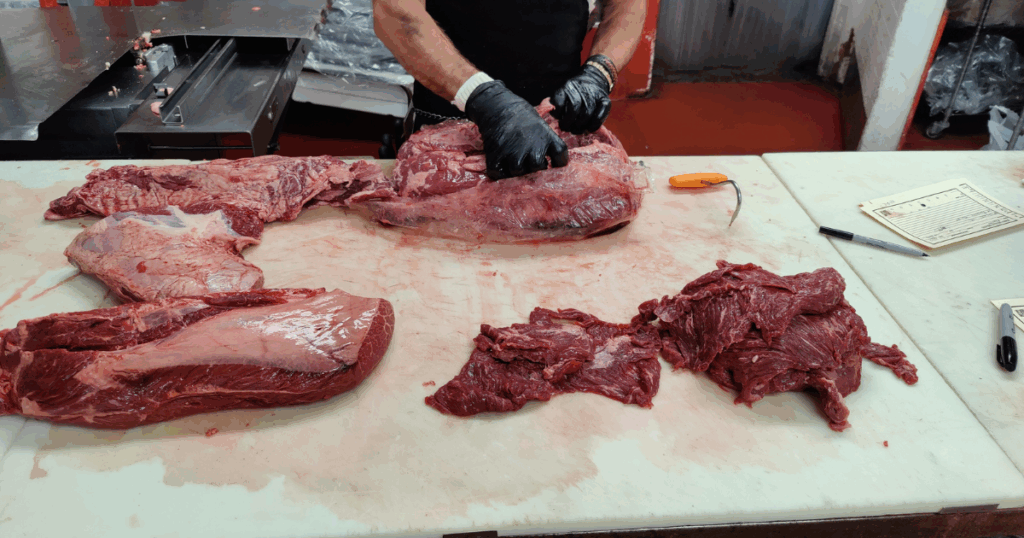 Skilled butcher in shop at John Mull’s Meats preparing high quality beef cuts inside the Las Vegas meat market known for award winning service and expert craftsmanship.
