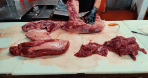 Owner and professional butcher hand-cutting fresh beef at John Mull’s Meats in Las Vegas, showcasing expert butchery and high-quality meat preparation