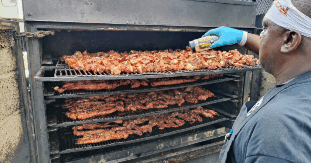 Pitmaster seasoning slow-smoked ribs inside the smoker at John Mull’s Meats & Road Kill Grill, a hidden barbecue destination in Northern Las Vegas