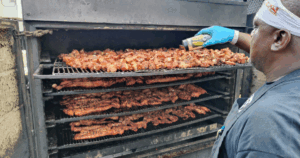 Pitmaster seasoning slow-smoked ribs inside the smoker at John Mull’s Meats & Road Kill Grill, a hidden barbecue destination in Northern Las Vegas