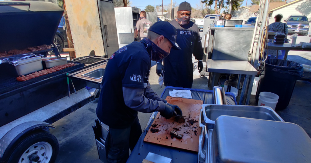 John Mull’s Road Kill Grill team preparing smoked meats outdoors at a Las Vegas BBQ restaurant known for family-friendly outdoor dining.