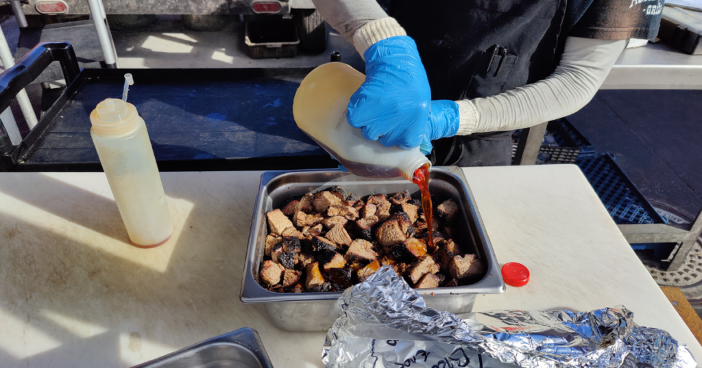 John Mull’s Road Kill Grill staff adding BBQ sauce to smoked meats at a Las Vegas meat market that was voted the best butcher and BBQ restaurant.