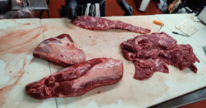 Professional butcher preparing premium beef cuts at a Las Vegas meat market using a commercial meat saw at John Mull's Meats.