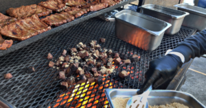 Burnt ends and smoked ribs cooking over a live wood-fired smoker at Road Kill Grill in Las Vegas BBQ restaurant.